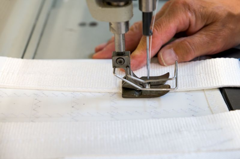 Costruzione di una vela da crociera, utilizzando una macchina da cucire industriale su un tessuto resistente, con dettagli delle cuciture e del materiale in primo piano