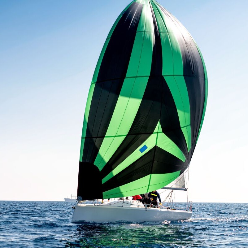 Immagine di una vela da regata in azione, navigando in mare con vento favorevole e onde visibili.